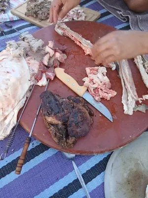 a table with a cutting board with meat and a knife at Agoudim Nikhartan in Tinerhir