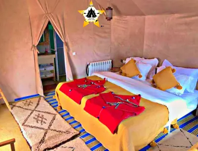 a bedroom with a large bed with red sheets at Merzouga Stellar Camp in Merzouga