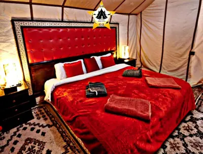 a bedroom with a large bed with a red blanket at Merzouga Stellar Camp in Merzouga