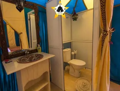 a bathroom with a toilet and a sink and a mirror at Merzouga Stellar Camp in Merzouga