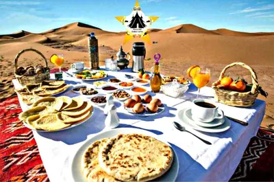 a table in the desert with food and drinks at Merzouga Stellar Camp in Merzouga