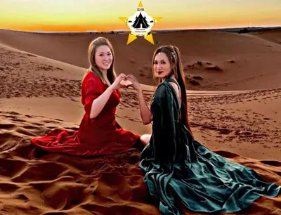 two girls sitting in the desert with a star at Merzouga Stellar Camp in Merzouga