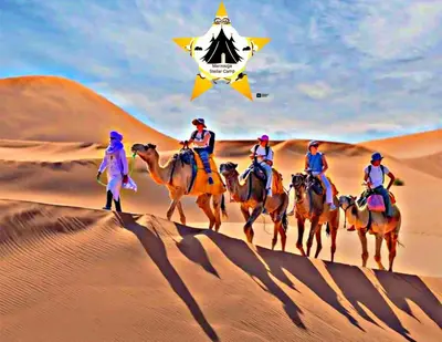 a group of people riding camels in the desert at Merzouga Stellar Camp in Merzouga