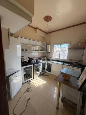 a large kitchen with white appliances and a table at Apparemment à 100 mètres du complexe de fes in Fès