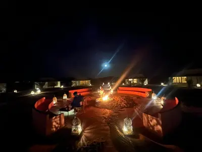 a person sitting at a table at night at Connect Nomad - Luxury Camp Merzouga in Merzouga