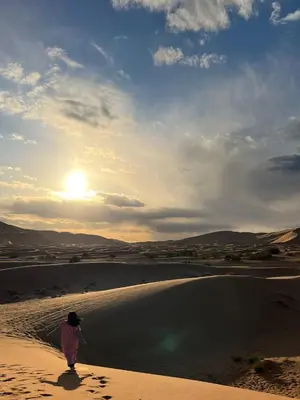 a woman walking on the sand in the desert at Connect Nomad - Luxury Camp Merzouga in Merzouga