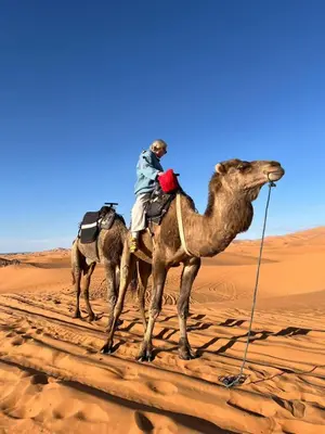 a man riding on a camel in the desert at Merzouga sunset camp in Merzouga