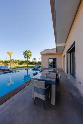 a patio with a table and chairs next to a swimming pool at Villa Dar E'Zwinna in Marrakech
