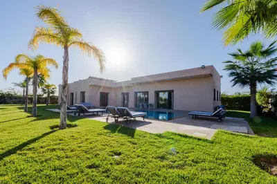 a house with palm trees in front of it at Villa Dar E'Zwinna in Marrakech