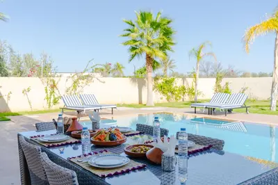 a table with food on it next to a swimming pool at Villa Dar E'Zwinna in Marrakech