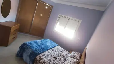 a bedroom with a bed with a blue blanket and a window at Bright & Calm Apartment in Riad Toulal in Meknès