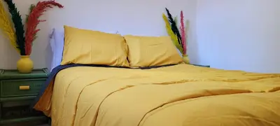 a bed with yellow sheets and pillows in a bedroom at Green Ourika Haven Relax Among Mountains Nature