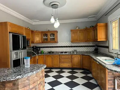 a kitchen with wooden cabinets and a checkered floor at la perle de fes in Fès