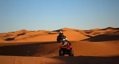 a person riding a quad bike in the desert at moroccan izem camp in Merzouga