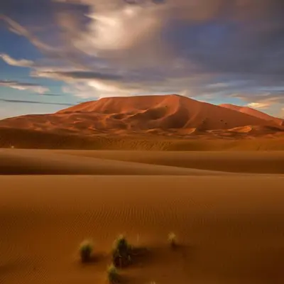 a desert with a sand dune in the background at moroccan izem camp in Merzouga