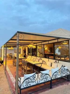 a pavilion with couches and tables on a patio at moroccan izem camp in Merzouga
