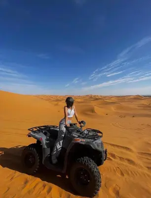 a woman riding a quad bike in the desert at moroccan izem camp in Merzouga