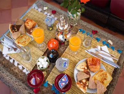a table with a tray of food and glasses of orange juice at Oasis apartment in Ouarzazate