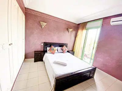 a bedroom with a bed with a purple wall at Appartement d'orient centre ville in Oulad Akkou