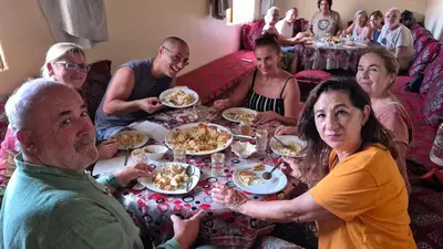 a group of people sitting around a table eating food at Dartagounite in Oulad Akkou