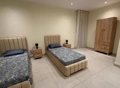 a bedroom with two beds and a wooden cabinet at la bella cita fes in Fès