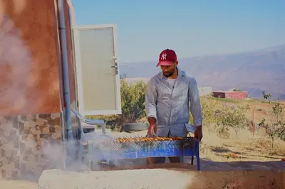 a man is cooking food on a grill at Gite les pommiers de tizi in Beni Mellal