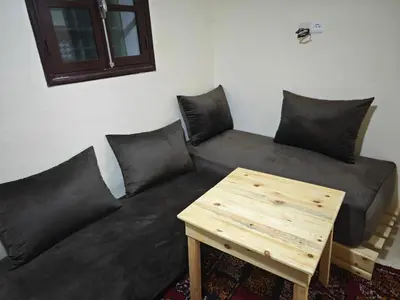 a black couch with pillows and a wooden table at Gite les pommiers de tizi in Beni Mellal