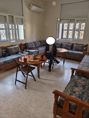 a person sitting on a couch in a living room at maison de tourisme el amal in Oulad Akkou