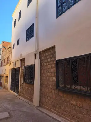 a building with two gates on the side of a street at maison de tourisme el amal in Oulad Akkou