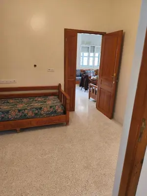 a bedroom with two beds and a door to a room at maison de tourisme el amal in Oulad Akkou