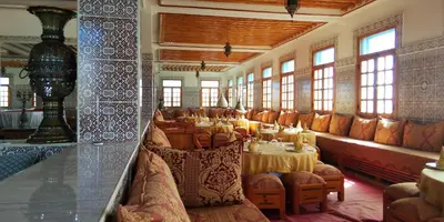 a dining room with tables and chairs and windows at hotel and restaurant kasbah draa in Agdz