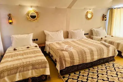 a bedroom with two beds and a mirror on the wall at Merzouga Dream Starlight in Merzouga