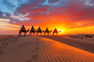 a group of people riding camels in the desert at sunset at Merzouga Dream Starlight in Merzouga