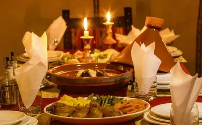 a table with plates of food on a table with candles at Merzouga Dream Starlight in Merzouga