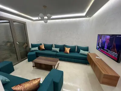 a living room with a blue couch and a tv at Résidence Saadia, Khouribga in Khouribga