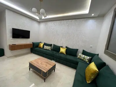 a living room with a green couch and a tv at Résidence Saadia, Khouribga in Khouribga