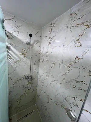 a bathroom with a shower with a marble wall at Résidence Saadia, Khouribga in Khouribga