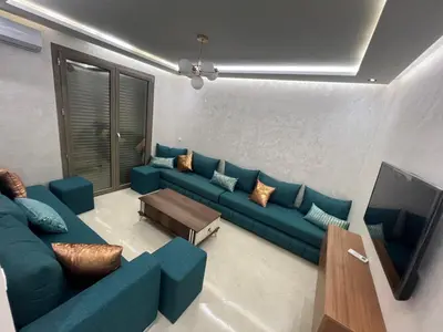 a living room with a blue couch and a tv at Résidence Saadia, Khouribga in Khouribga