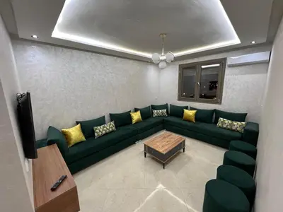 a living room with a green couch and yellow pillows at Résidence Saadia, Khouribga in Khouribga