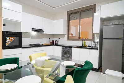 a kitchen with a glass table and green chairs at URBAN WHITE Elya 1 in Beni Mellal
