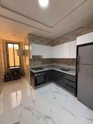a kitchen with white marble floors and a refrigerator at Kamlia meknes in Meknès