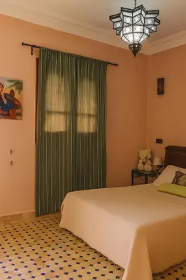 a bedroom with a bed and a window with green curtains at Villa d'Exception à Ourika Nichée au Cœur des Montagnes in Aghbalou