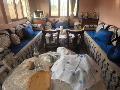 a living room with a couch and a table and chairs at Dar lamane in Tamnougalt