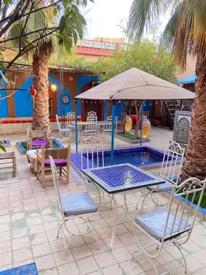 a patio with chairs and a table and an umbrella at Riad Dades Birds Lodge in Boumalne