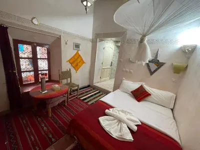 a bedroom with a bed and a table and a window at Riad Dades Birds Lodge in Boumalne