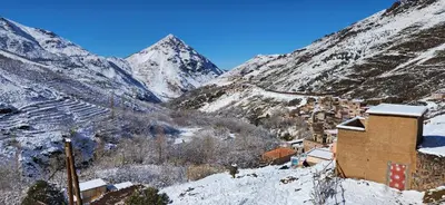 a snow covered mountain with a town and a building at Dar Agourzi Café des Epices in Tacheddirt