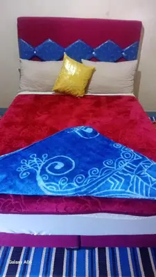 a bed with a red and blue blanket and pillows at Dar Agourzi Café des Epices in Tacheddirt