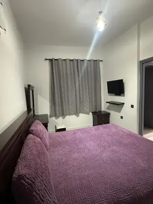 a bedroom with a purple bed and a television at Appartement pour les familles in Fès