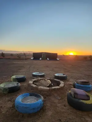 a group of tires in the desert with the sunset at Camping Meteorite in Merzane