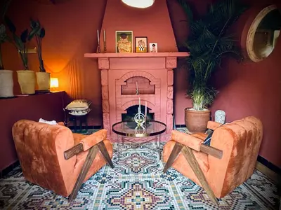 a living room with two chairs and a fireplace at villa lalla Ourika & heated pool in Oulad Akkou